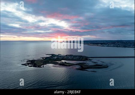 Ungewöhnliche Luftaufnahme von Hammelinseln bei Sonnenuntergang, die die gesamte Insel und einen Teil des Dammes erfasst. Der dramatische Himmel bietet eine atemberaubende Kulisse. Stockfoto