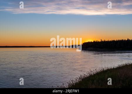 Wunderschöner orangenrosafarbener Sonnenuntergang über dem Mackenzie River in der Nähe von Fort Providence, NT Canada Stockfoto