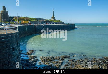 The Front at Aberystwyth sonniger Apriltag entlang der Küste mit einer Sea Defence Mauer sowie einem Denkmal, Geländer und einem Teil des alten Schlosses Stockfoto