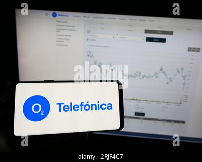 Person, die ein Mobiltelefon mit dem Logo der Firma Telefonica Deutschland Holding AG auf dem Bildschirm vor der Webseite hält. Konzentrieren Sie sich auf das Display des Telefons. Stockfoto