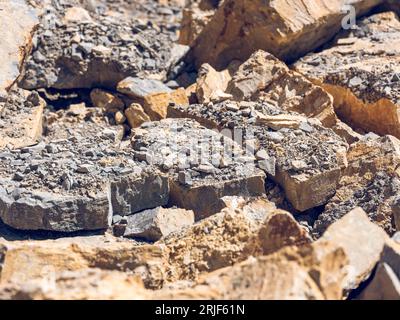Hintergrund von rauen, gerissenen, hellen, unordentlichen Steinen mit verstreuten Felsen über den Steinen an sonnigen Tagen Stockfoto