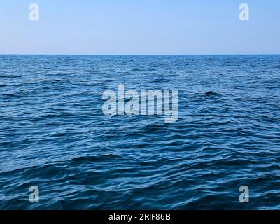 Ruhiges blaues Wasser am Lake Michigan mit blassblauem Himmel über dem Horizont Stockfoto