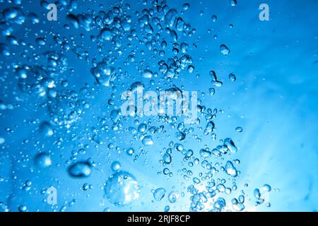 Textur von abstrakten Luftblasen unterschiedlicher Grösse auf Gradientenhintergrund von lebhaftem azurblauem Wasser Stockfoto