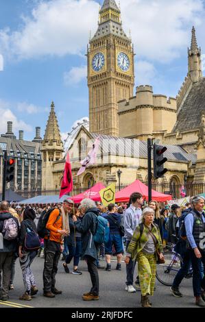 LONDON – 22. April 2023: Der legendäre Stand von XR: Big Ben und das London Eye dienen als markante Kulissen, während Demonstranten beim Klimaprotest die XR-Flaggen schwenken Stockfoto