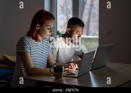Seriöser schwarzer Mann und Frau, die an Laptops arbeiten. Fokussierte Mitarbeiter konzentrieren sich auf Online-Arbeit Stockfoto