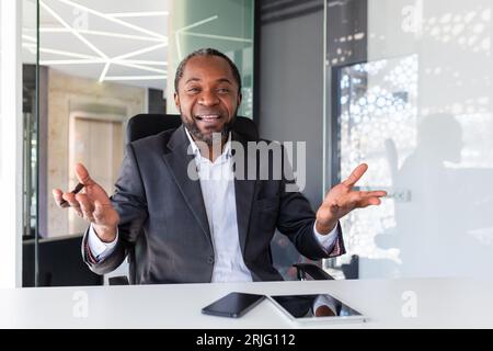 Videoanruf Online-Meeting, afroamerikanischer Geschäftsmann-Chef lächelt und schaut Kamera an, Mann im Geschäftsanzug reifer, der Spaß hat, mit Kollegen zu sprechen, auf virtuellem Meeting im Büro aus der Ferne. Stockfoto