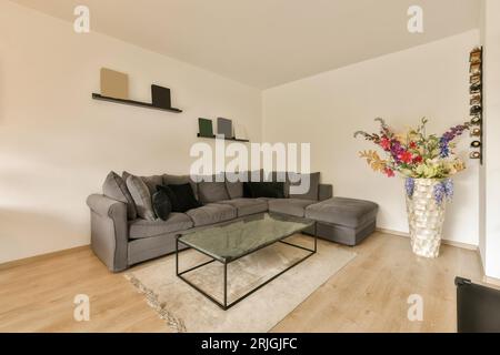 Ein Wohnzimmer mit Sofas und Blumen in der Vase auf dem Couchtisch neben dem Sofa ist grau Stockfoto