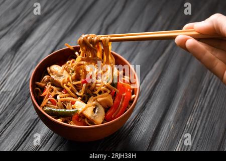 Teller mit Buchweizennudeln mit Gemüse, Pilzen, Hähnchenfleisch auf dunklem Hintergrund, Draufsicht. Chinesische Stäbchen nehmen japanische Soba Stockfoto