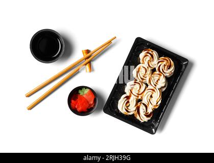 Sushi-Brötchen mit Lachs, gekrönt mit Frischkäse und Sauce in einer Plastikverpackung, Essstäbchen, Ingwer, Sauce auf weißem Hintergrund. Stockfoto