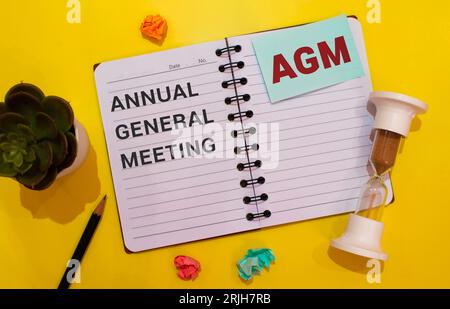 Desktop-Lupe, Berichte, Stift und Notizbuch mit Text AGM Jahreshauptversammlung. Geschäftskonzept Stockfoto