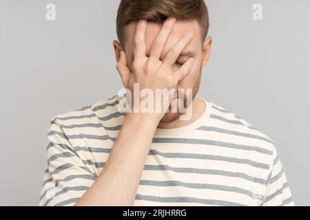 Enttäuschter gestresster Mann mittleren Alters, der eine Facepalm-Geste macht und sich selbst für einen Fehler verantwortlich macht Stockfoto