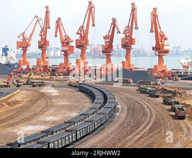 YANTAI, CHINA - 22. AUGUST 2023 - Frachtschiffe und -Züge transportieren Kohle im Longkou-Hafengebiet im Yantai-Hafen in der ostchinesischen Provinz Shandong, 22. August 2 Stockfoto