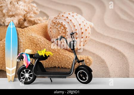 Elektroroller mit hölzernem Surfbrett in der Nähe der Wand mit bedruckter Meeresmuschel und Seestern Stockfoto