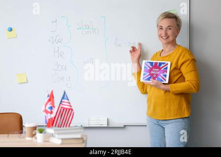 Lehrerin mit Tablet-Computer und Text LERNT IM Klassenzimmer ENGLISCH Stockfoto
