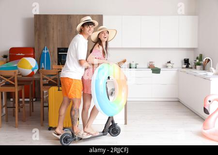 Junges Paar mit Strandaccessoires bereit für den Sommerurlaub in der Küche Stockfoto