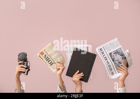 Weibliche Hände mit verschiedenen Zeitungen, Notebook und Mikrofon auf farbigem Hintergrund Stockfoto