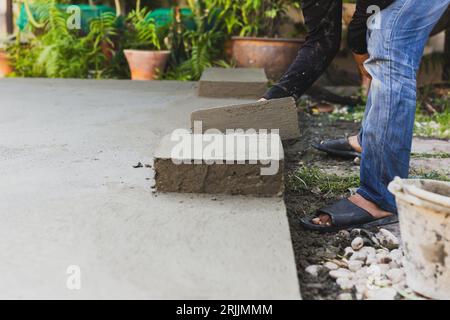 Arbeiter, die Betonzementböden mit Kelle ebnen. Stockfoto