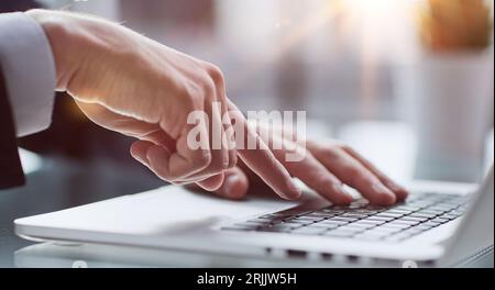 Junger Mann drückt seinen Finger auf den Computer am Tisch im Büro, Nahaufnahme. Stockfoto