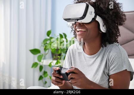 Afrikanerin genießt Videospiele mit VR-Headset auf dem Bett. Stockfoto