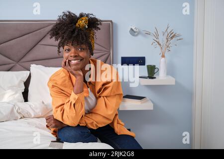 Fröhliche Afrikanerin mit einem strahlenden Lächeln in ihrem Schlafzimmer. Stockfoto