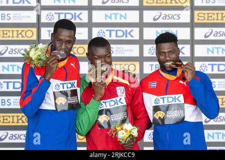 Budapest, Ungarn. August 2023. Hugues Fabrice Zango (C) von Burkina Faso, Lazaro Martinez (L) und Cristian Napoles von Kuba posieren auf dem Podium während der Verleihung des Dreifachsprungs der Männer der Leichtathletik-Weltmeisterschaften Budapest 2023 in Budapest, Ungarn, 22. August 2023. Quelle: Meng Dingbo/Xinhua/Alamy Live News Stockfoto