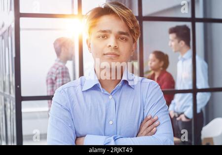 Porträt eines selbstbewussten Jungen, der mit dem Kreuz in den Armen steht Stockfoto