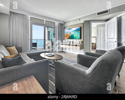 Dieser moderne Wohnbereich verfügt über zwei graue Sofas und Glastüren mit atemberaubendem Blick auf das Meer Stockfoto