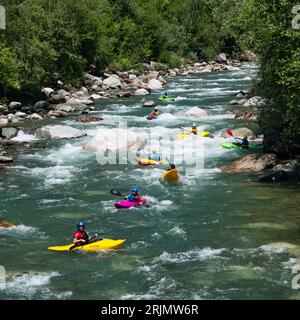 Eine Gruppe von Kajakfahrern genießen einen sonnigen Tag auf einem Fluss, der sich zwischen den Felsen bewegt. Stockfoto