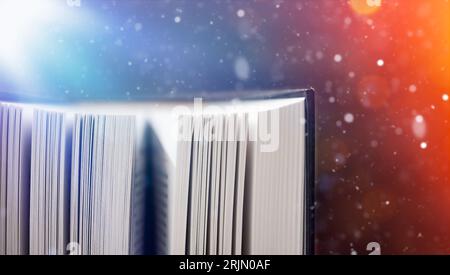 Geheimnisvolles offenes Buch. Fantasy-Buch mit magischem Licht. Magisches altes Buch mit abstrakten Bokeh-Lichtern, die in der Dunkelheit leuchten. Literatur und Märchenkonzept. Stockfoto