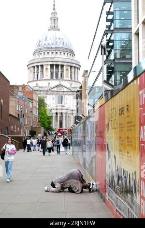 Obdachloser Mann, der auf der Straße bettelte und sich auf dem Bürgersteig in der Nähe der St Pauls Cathedral in der City of London, England, Großbritannien, 2023 KATHY DEWITT niederkniete Stockfoto