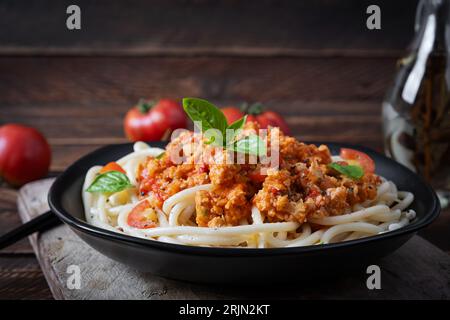 Spaghetti-Nudeln und Tomatensauce mit Hähnchenhack auf Holzuntergrund. Pasta Bolognese. Stockfoto