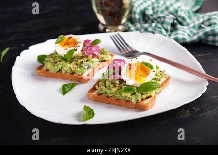 Gesunder Toast mit Avocado-Püree, gekochten Eiern, Gewürzen und roten Zwiebeln. Köstliches Frühstück oder Snack. Stockfoto