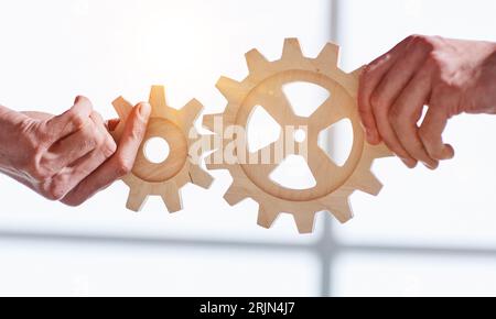 Zwei Geschäftsleute vereinen Zahnräder aus Holz, Nahaufnahme Stockfoto