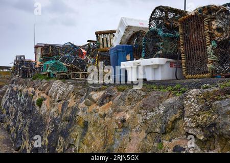 A pile of lobster traps and plastic boxes line the harbour wall at St Abbs Stockfoto