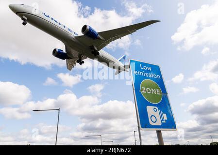 Schild für emissionsarme Zonen mit Landung eines Düsenflugzeugs am Flughafen London Heathrow, Großbritannien. Luftverschmutzung. Kohlendioxidemissionen. Luftverkehrsemissionen. Kamerabild Stockfoto