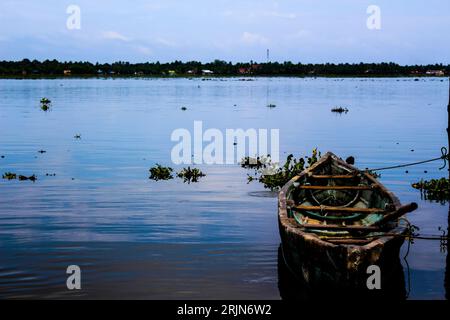 Ein kleines Boot liegt an einem Pier in einem ruhigen Gewässer Stockfoto