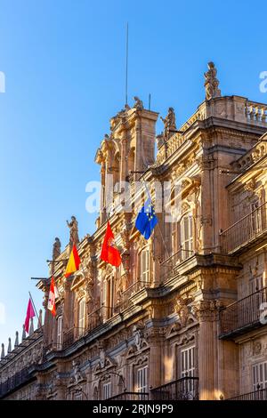 Salamanca Rathaus barocke Gebäudefassade auf der Plaza Mayor, mit Reliefs, Skulpturen und Fahnen, Blick auf den Sonnenuntergang. Stockfoto