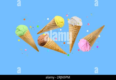 Eislöffel in Waffelkegeln fliegen auf blauem Hintergrund. Stockfoto