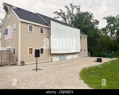 Große Filmleinwand an der Seite einer braunen Scheune mit amerikanischer Flagge Stockfoto