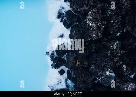 Luftaufnahme der atemberaubenden Berglandschaft von Reykjavik, Island, mit schroffen, schneebedeckten Felsen und einem ruhigen Gewässer Stockfoto