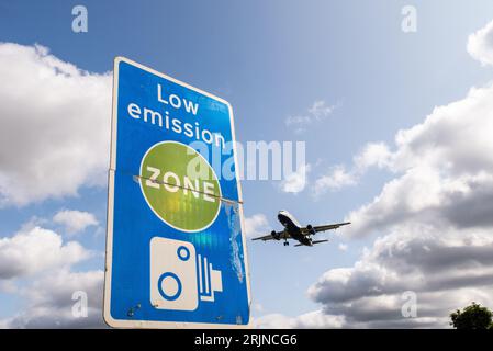 Schild für emissionsarme Zonen mit Landung eines Düsenflugzeugs am Flughafen London Heathrow, Großbritannien. Luftverschmutzung. Kohlendioxidemissionen. Luftverkehrsemissionen. Kamerabild Stockfoto