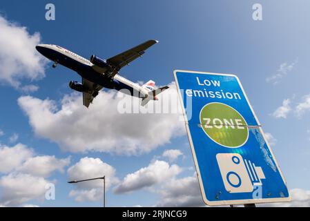 Schild für emissionsarme Zonen mit Landung eines Düsenflugzeugs am Flughafen London Heathrow, Großbritannien. Luftverschmutzung. Kohlendioxidemissionen. Luftverkehrsemissionen. Kamerabild Stockfoto