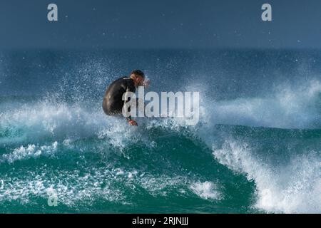 Spektakuläre Surfaktion als männlicher Surfer reitet auf einer Welle im Fistral in Newquay in Cornwall in England in Großbritannien. Stockfoto