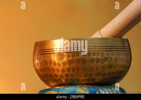 Eine kunstvolle, handgehämmerte tibetische Glocke auf goldenem Hintergrund Stockfoto