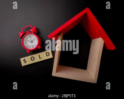 Holzhaus mit Blick von oben und Uhr mit Wort auf schwarzem Hintergrund Stockfoto