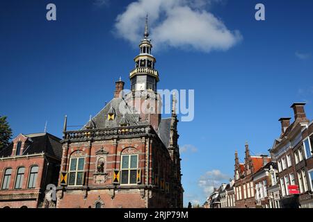Die kunstvolle und farbenfrohe Architektur des Rathauses im Renaissance-Stil von Bolsward, Friesland, Niederlande, mit historischen Häuserfassaden auf der rechten Seite Stockfoto