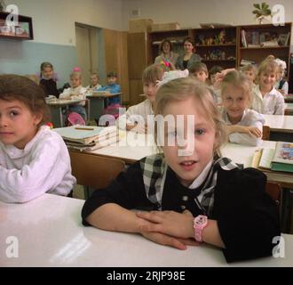 Wolgograd, Russland - Januar 1996: Gescanntes Filmbild eines Schülers der ersten Klasse in Wolgograd, Russland (ehemals Stalingrad). Der Lehrer und die Mutter hinten. Stockfoto