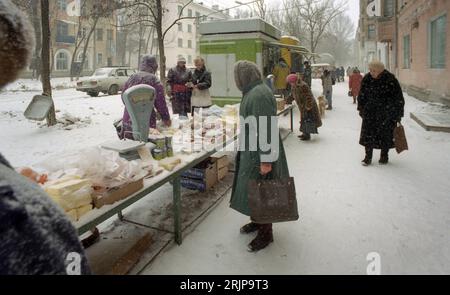 Wolgograd, Russland - Januar 1996: Gescanntes Filmbild von russischen Frauen, die im Winter auf einem schneebedeckten Bürgersteig einkaufen. Editorial. Stockfoto