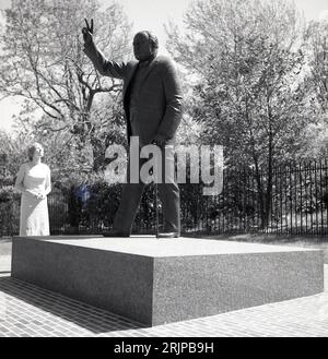 1960er Jahre, historisch, Washington DC, USA, Sommer und eine Dame, die die Bronzeskulptur von Winston Churchill, Großbritanniens berühmtem Premier Minster aus der Kriegszeit, betrachtet und sein traditionelles V for Victory-Zeichen zeigt. Stockfoto