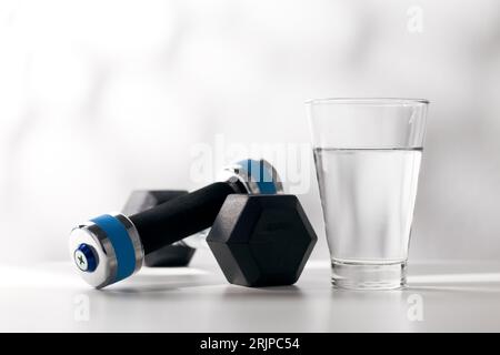 Kurzhanteln und Trinkwasser im Glas nach dem Training. Stockfoto